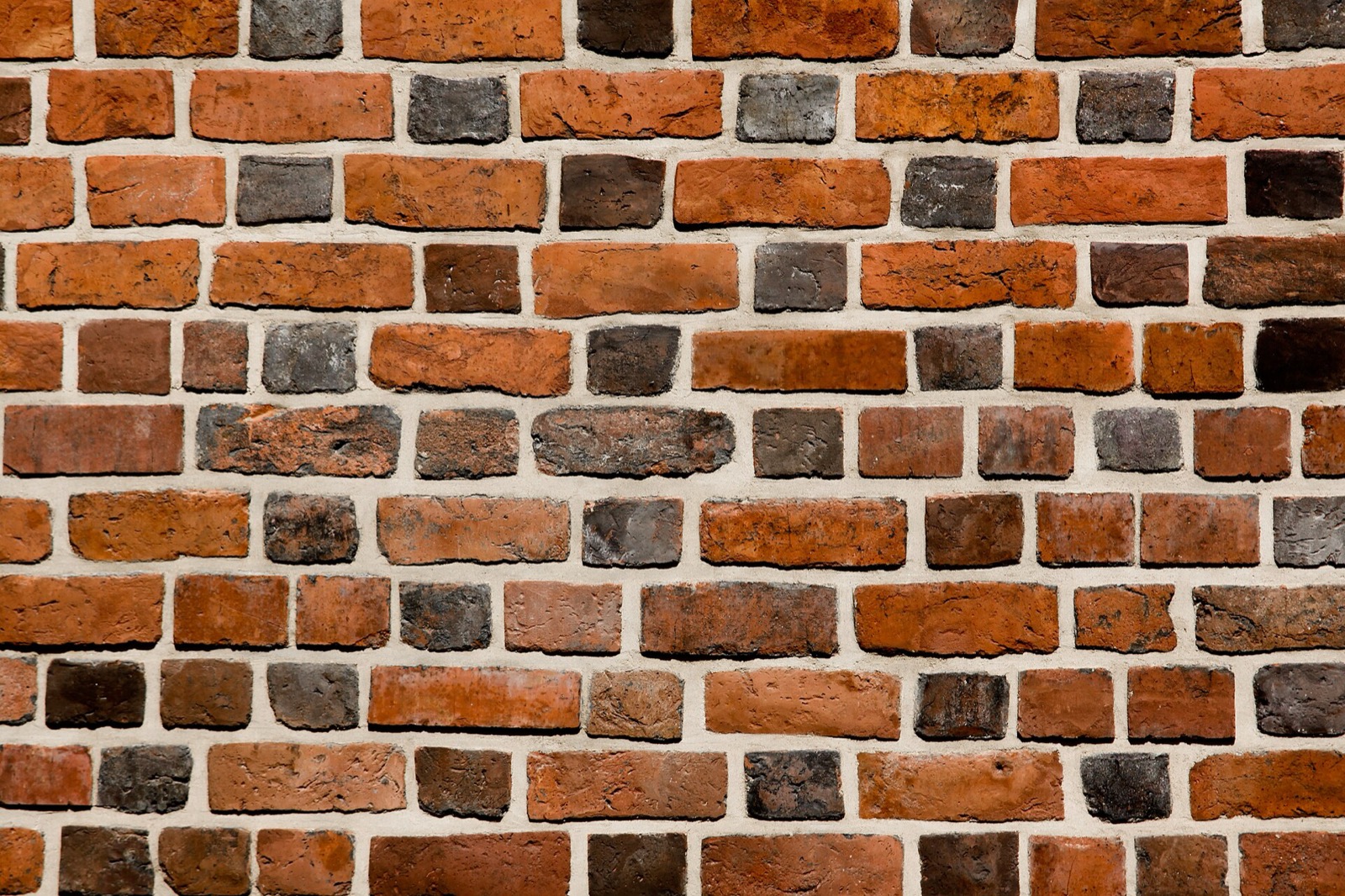 Close view of a brick wall in mixed reds and dark browns with pale mortar joints
